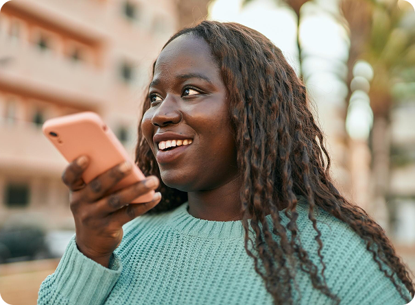Two women smiling and engaging in community work, one holding a tablet